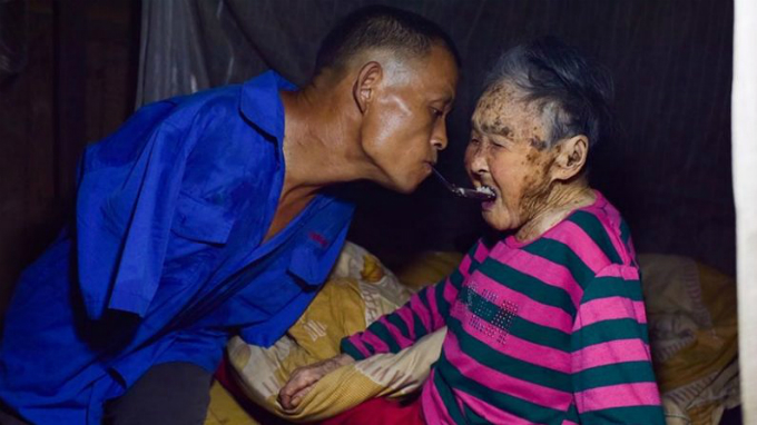 Con trai mất cả hai tay giữ thìa bằng răng để bón cơm cho mẹ