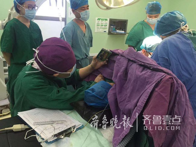 Y tá ân cần quỳ bên bàn mổ suốt cả tiếng đồng hồ để cầm điện thoại cho bệnh nhi xem hoạt hình