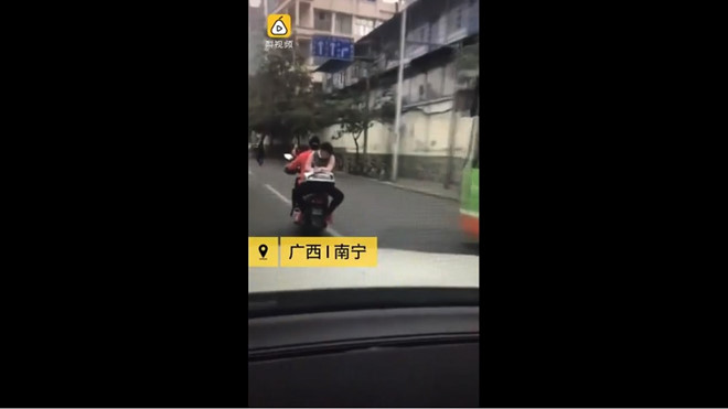 Nữ sinh tranh thủ làm bài tập khi ngồi ngược sau xe máy