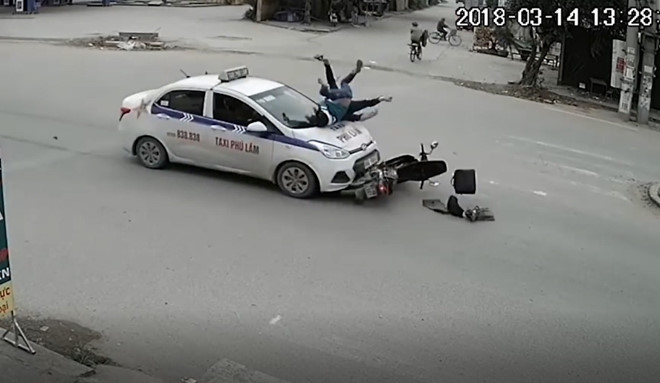 Phóng nhanh qua ngã tư, 2 người đi xe máy bị taxi hất lên nắp capo