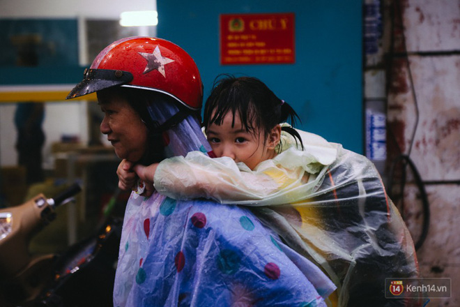 Phụ huynh ẵm bồng con nhỏ, bì bõm lội nước về nhà sau cơn mưa lớn ở Sài Gòn