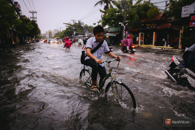 Phụ huynh ẵm bồng con nhỏ, bì bõm lội nước về nhà sau cơn mưa lớn ở Sài Gòn