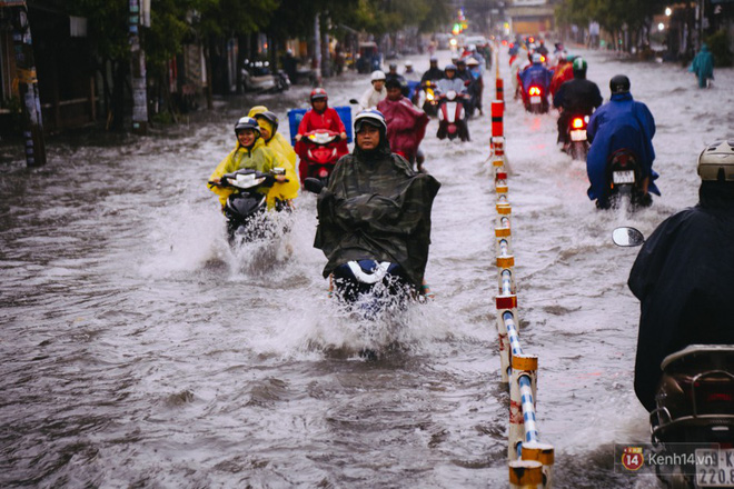 Phụ huynh ẵm bồng con nhỏ, bì bõm lội nước về nhà sau cơn mưa lớn ở Sài Gòn