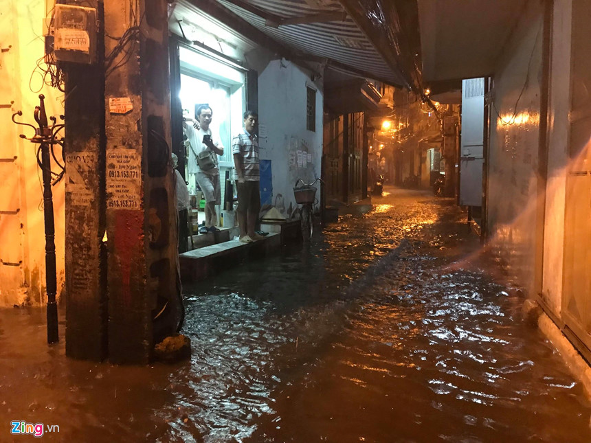 Mưa lớn trút xuống, người co chân ngồi nhậu, kẻ hì hục tát nước