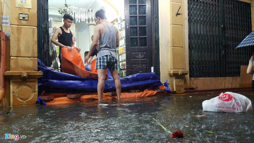 Mưa lớn trút xuống, người co chân ngồi nhậu, kẻ hì hục tát nước