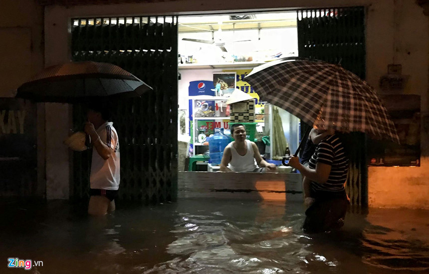 Mưa lớn trút xuống, người co chân ngồi nhậu, kẻ hì hục tát nước