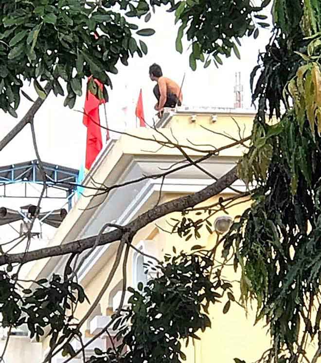 Thanh niên nghi ngáo đá leo lên nóc nhà kho bạc ngồi ngẩn ngơ