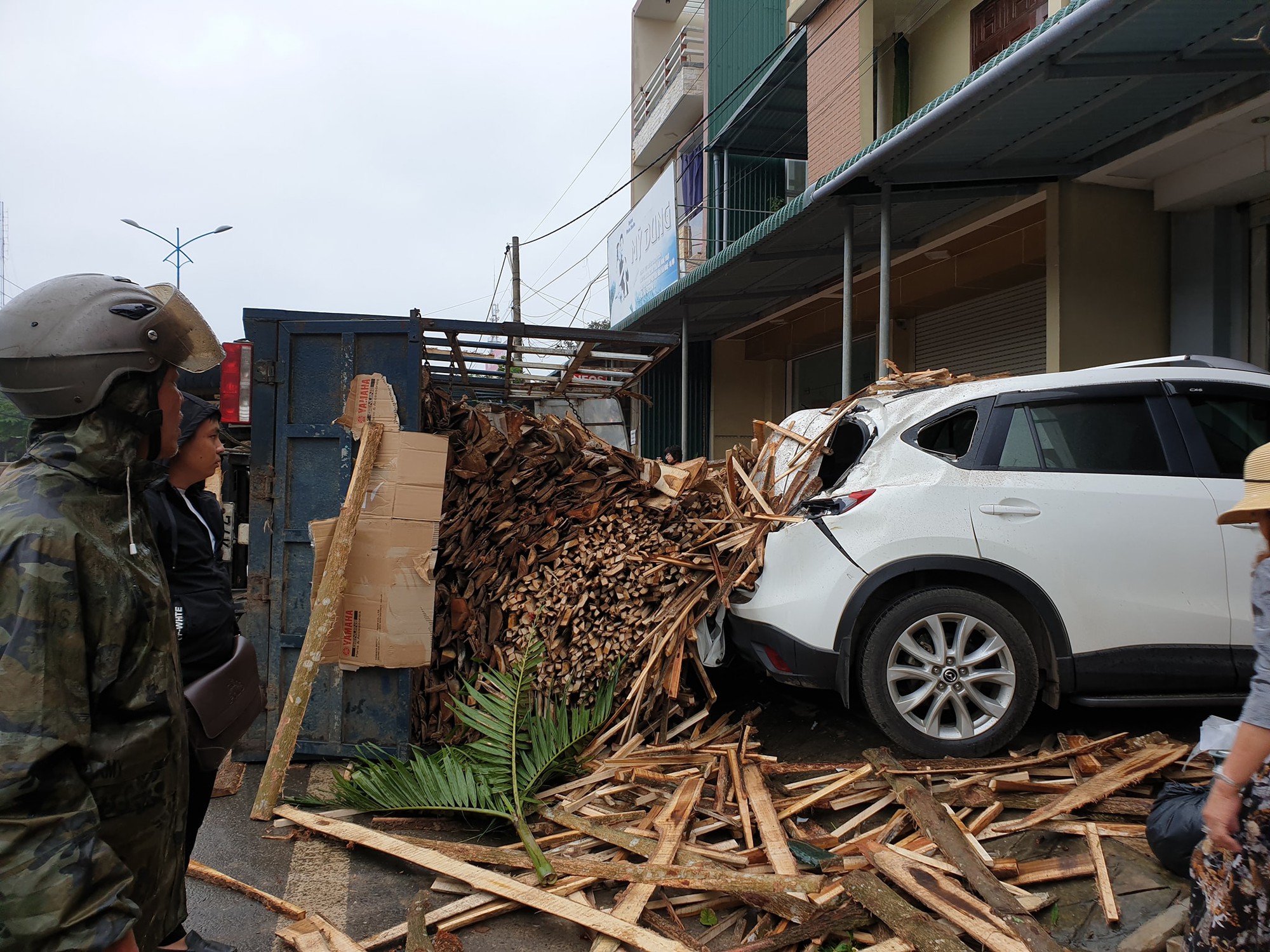 Clip: Tránh cụ ông đạp xe băng qua đường, xe tải chở gỗ lật ngang rồi đè móp đuôi xế hộp CX5