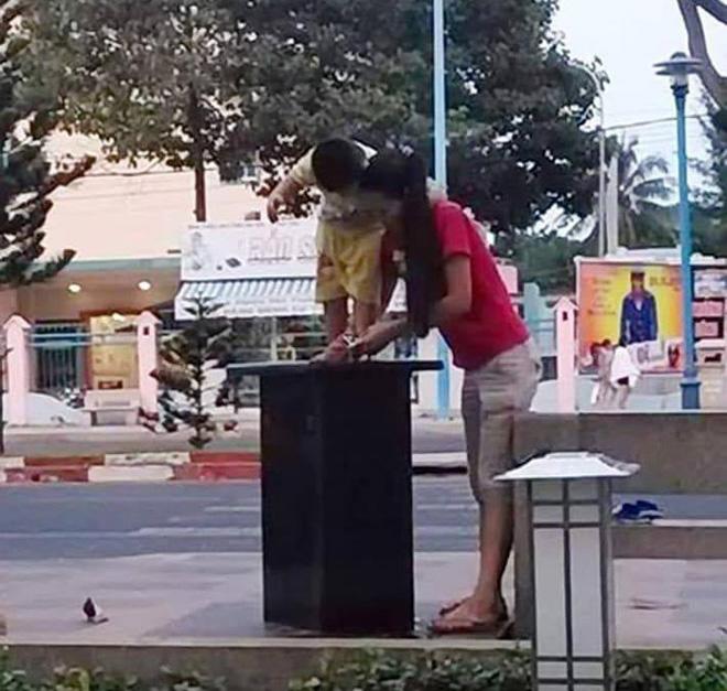 Mẹ bế con trai rửa chân nơi ven đường, cư dân mạng phẫn nộ vì chi tiết này