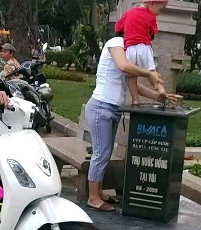 Mẹ bế con trai rửa chân nơi ven đường, cư dân mạng phẫn nộ vì chi tiết này