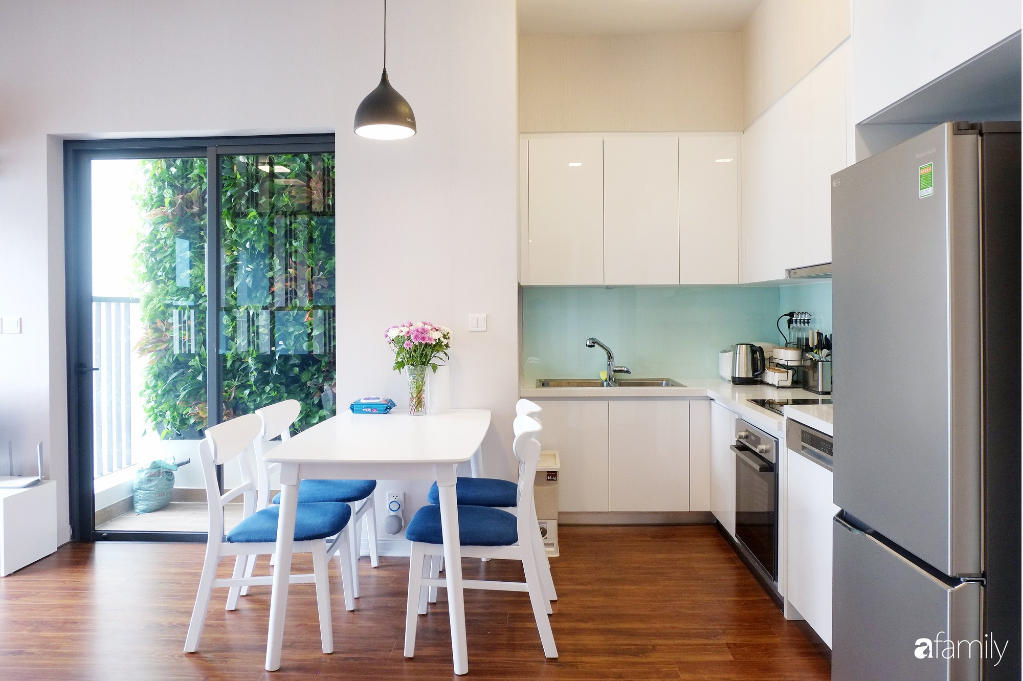 Không gian bếp được cải tạo bằng cách lắp đặt cánh tủ gỗ công nghiệp màu trắng sáng, phân bố lại các khoang chứa đồ bên trong.