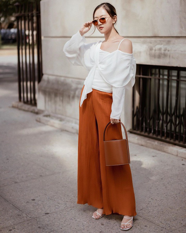 Áo blouse trắng cách điệu được cô nàng này kết hợp khá ăn ý cùng quần culottes nâu cam cùng sandals quai mảnh.