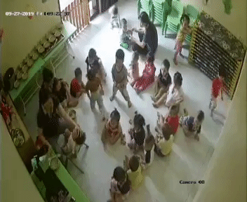 Cháu bé bị đè ngửa ra ghế để đút cháo.