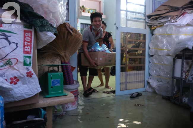 Người đàn ông ôm đồ dưới đất lên cao cho khỏi ướt.