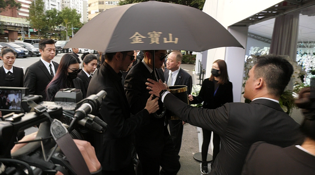 Hôn thê Bella của nam diễn viên đeo khẩu trang, kính đen, cúi gằm mặt. Cô cũng là người đau đớn không khá gì bố mẹ Cao Dĩ Tường khi anh qua đời.