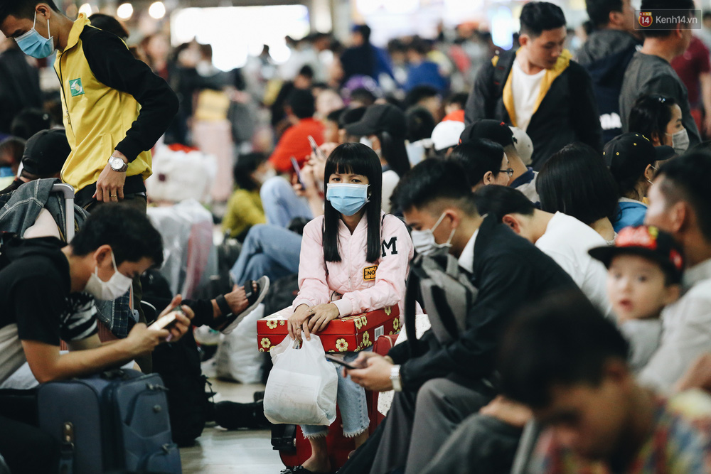 Nữ hành khách ôm thùng quà Tết mệt mỏi giữa nhà chờ bến xe ken đặc người.