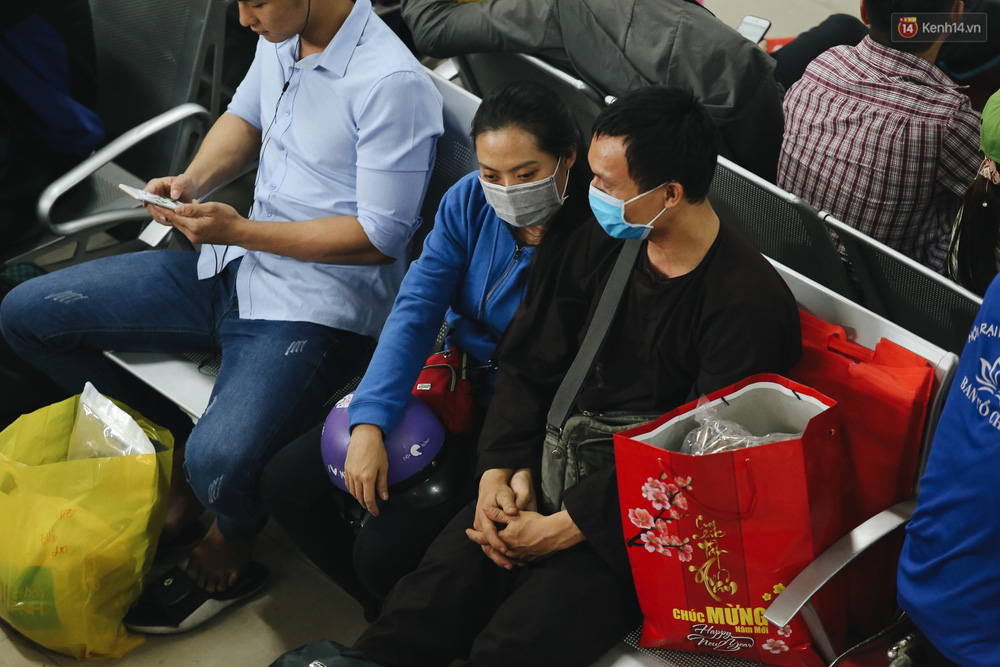 Hai vợ chồng tựa vào nhau cho đỡ mệt trong lúc chờ đợi lên xe.