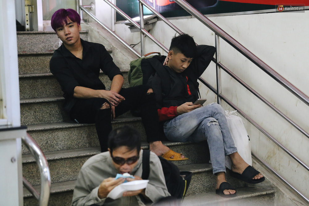 Hàng ghế kín chỗ nên hành khách phải ngồi cầu thang lối đi lại trong bến xe. Có người ăn tạm chiếc bánh bao chống đói trong lúc chờ đợi.