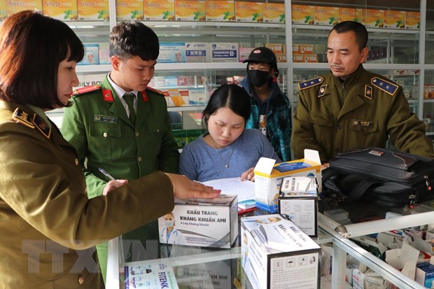 Lực lượng chức năng lập biên bản xử phạt hiệu thuốc bán khẩu trang không niêm yết giá (ảnh: Vietnamplus).