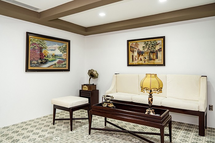 Một góc phòng giải trí đi theo phong cách cổ điển với gạch bông, điện thoại bàn và máy hát cổ.