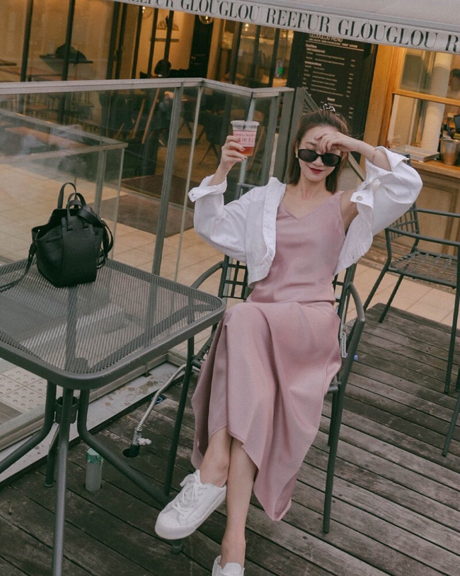 Sự xuất hiện của đôi sneakers trắng đã giúp set đồ bao gồm váy hai dây thướt tha, bay bổng + áo sơ mi trắng phóng khoáng trở nên thú vị và sành điệu hơn hẳn.