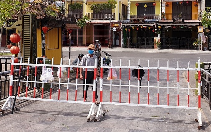 Người dân ở Hội An ra khu vực hàng rào phong tỏa khối phố An Hội, phường Minh An nhận thực phẩm. Ảnh: Đắc Thành.