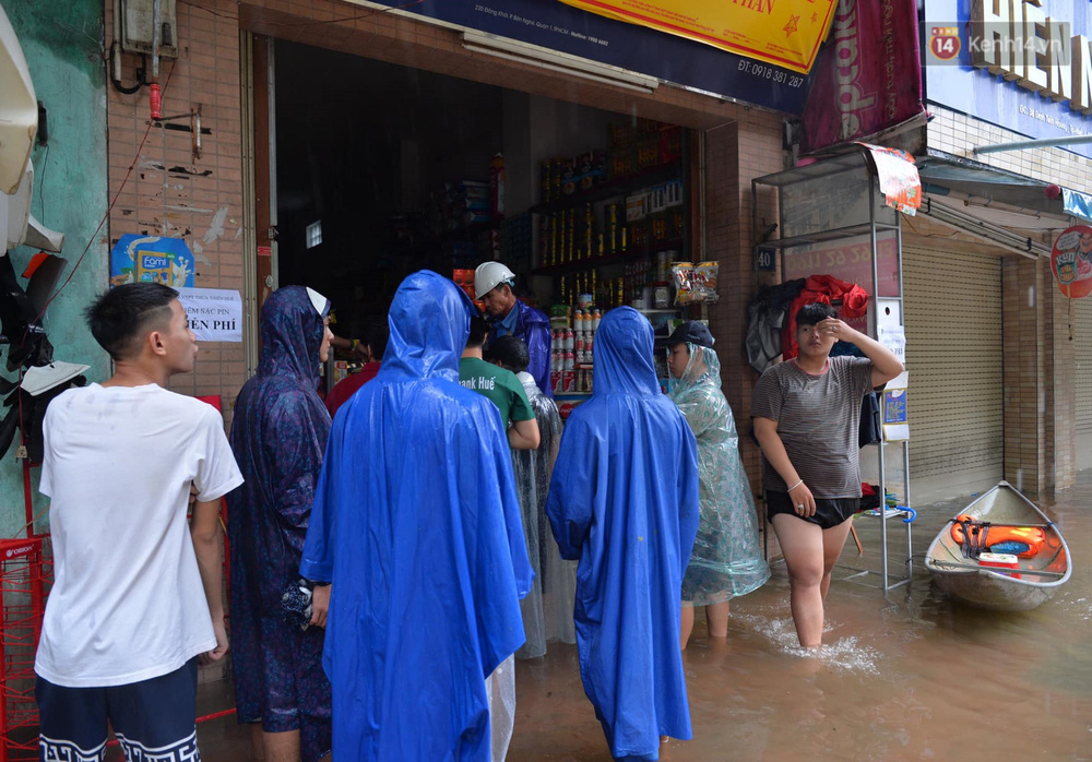 Khá nhiều người dân đứng đội mưa chờ sạc điện thoại, đèn tại tiệm tạp hoá này