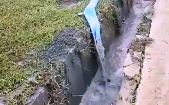 Nước từ bãi tro xỉ bơm ra mương thoát nước mưa có màu đen xám, đặc quánh. Ảnh cắt từ clip trên báo GD&TĐ.