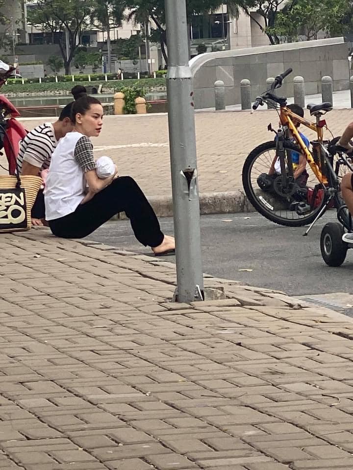 Cặp đôi thoải mái ngồi trên vỉa hè, vừa ôm con vừa nói chuyện với mọi người. (Nguồn: Trần Bảo)