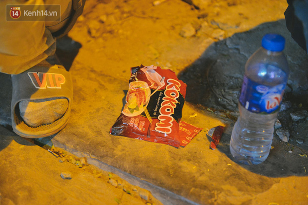 Ngồi co ro bên cạnh lề đường, ông Khánh ăn mì tôm, uống nước lọc để 