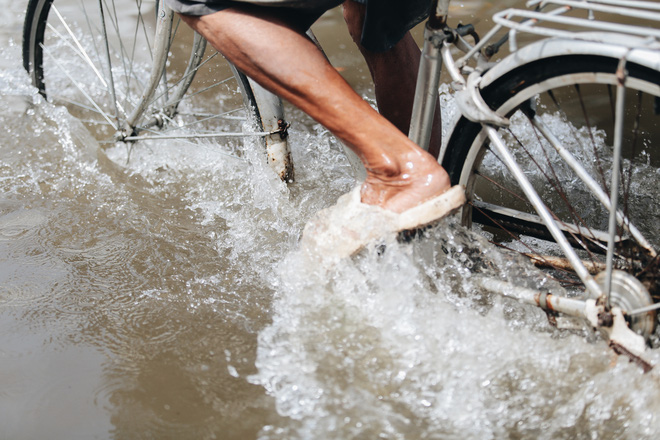 Người đi xe đạp vất vả lội nước cao gần bằng đầu gối