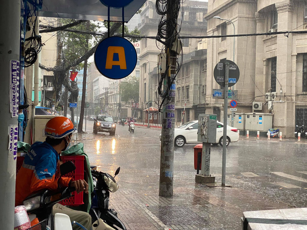 Nhân viên giao hàng trú mưa ở quận 1