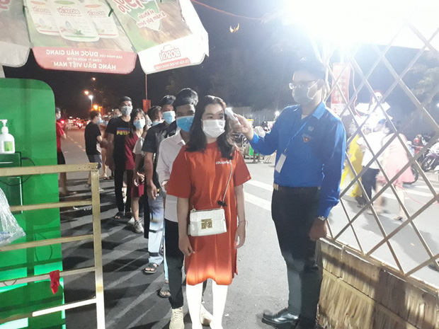 Khách xếp hàng, đeo khẩu trang và được đo thân nhiệt trước khi vào đường hoa nghệ thuật Cần Thơ