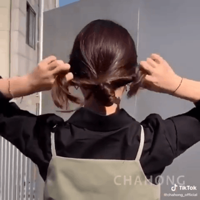 Đầu tiên bạn cần buộc đuôi ngựa thấp sau đó gập tóc lại, phần đuôi thừa tách ra làm đôi và cuộn lại quanh phần búi tóc rồi cố định bằng dây chun. Chỉ 2 thao tác đơn giản bạn đã có ngay kiểu tóc búi thấp cực sang mặt rồi.