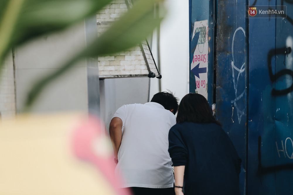 Hai người dân phải xếp hàng từng lượt để chui qua khoảng hở này bên rào chắn công trình