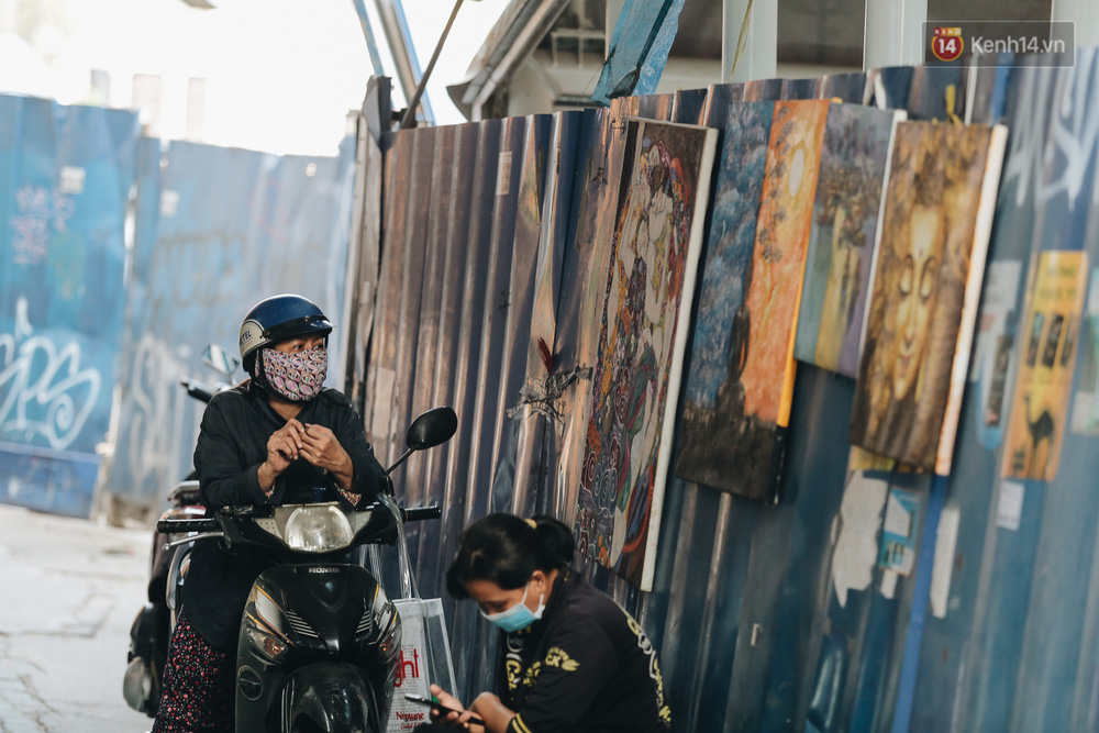Một cửa hàng bán tranh tận dụng hàng rào công trình để treo tranh cho khách ra vào nhận biết nhưng rất ít người ghé mua