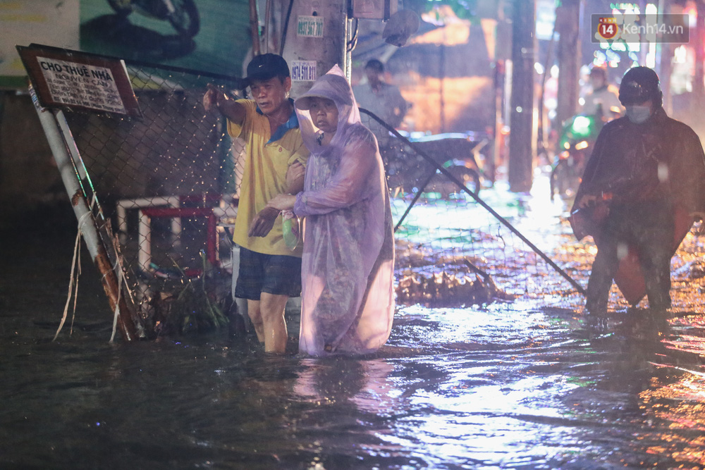 Người phụ nữ phải bám chặt tay người đàn ông vì sợ nước chảy xiết quật ngã khi lội bộ