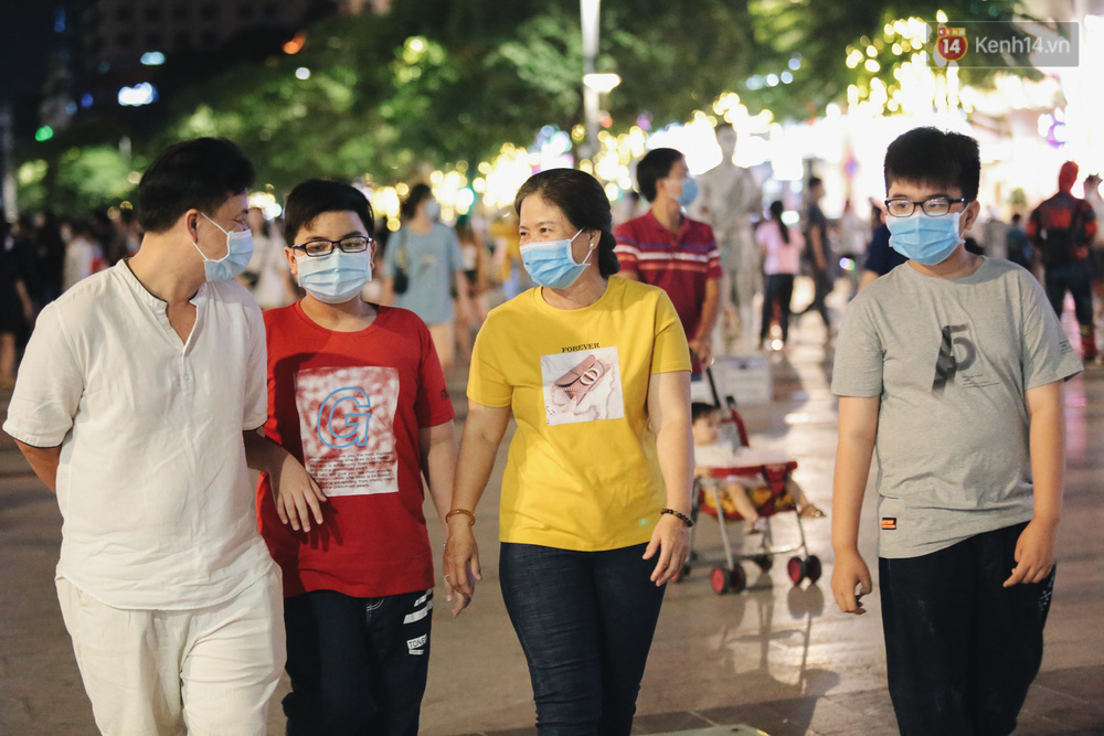 Cả gia đình đi dạo chơi ở phố đi bộ Nguyễn Huệ vui vẻ nói chuyện mà không quên đeo khẩu trang phòng dịch