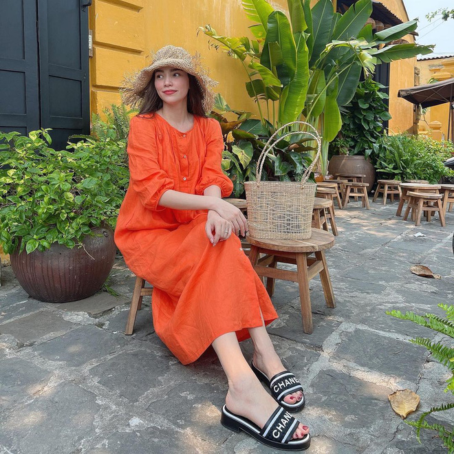 Hà Hồ diện váy màu cam xinh tươi, rạng rỡ. Để hoàn thiện vẻ xinh tươi cho tổng thể, Hà Hồ đã rất khéo léo khi nhấn nhá mũ và túi xách cói. Đôi dép lê bản to cô chọn cũng rất hợp với nét nhẹ nhàng, bay bổng của outfit và đảm bảo sự thoải mái, mát mẻ trong những ngày hè nóng nực