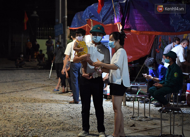 Một gia đình bế em bé ra để chờ đợi giây phút này, việc cách ly toàn bộ thôn được thực hiện từ ngày 30/4