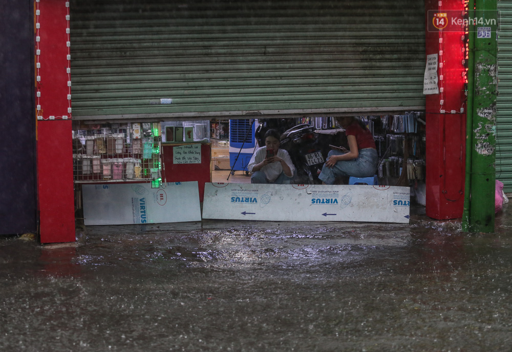 Người dân vất vả dùng vật dụng để ngăn nước tràn vào nhà, việc buôn bán bị đình trệ