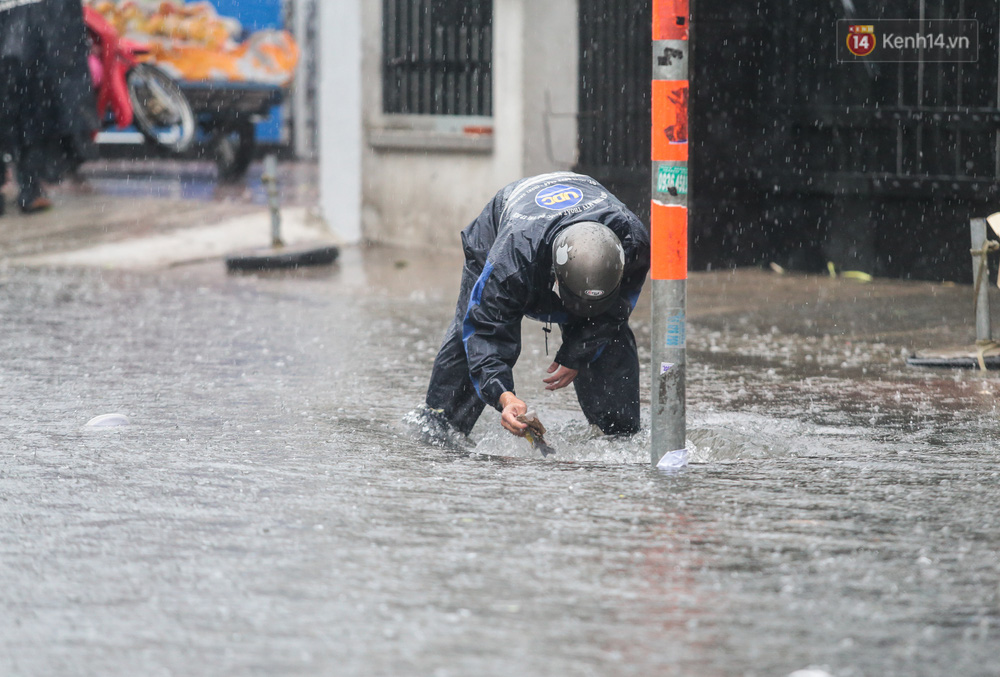 Người đàn ông liên tục vớt rác miệng cống để khơi thông dòng chảy nhưng nước vẫn rất lâu rút