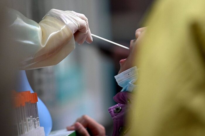 Nhân viên y tế lấy mẫu xét nghiệm cho một bé gái ở Bắc Kinh. Ảnh: AFP