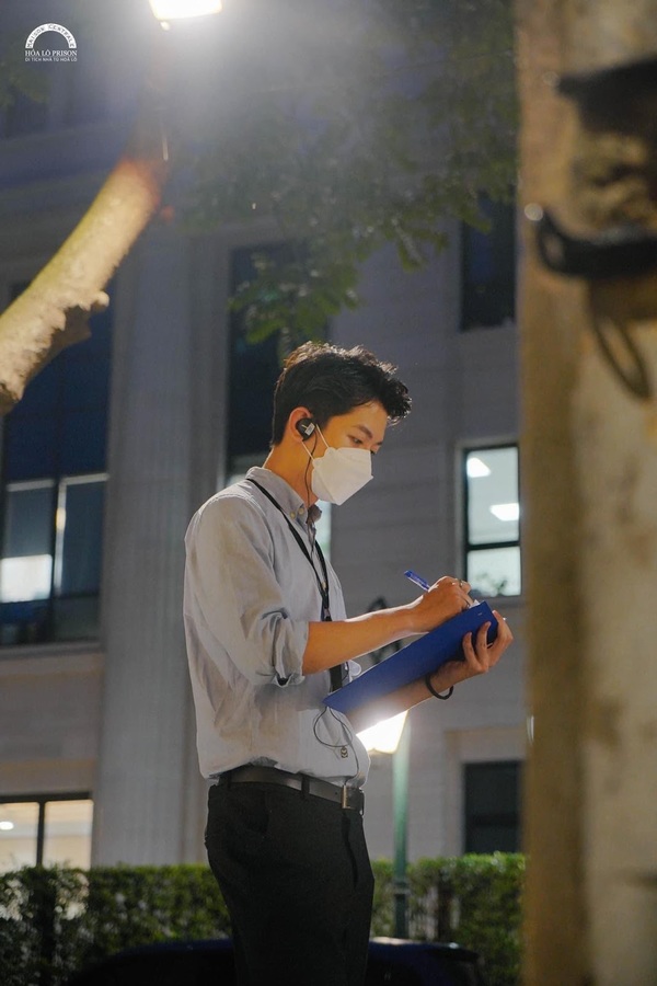 Trong ảnh, Thanh Tùng mặc áo sơmi đồng phục chỉn chu, đeo khẩu trang và bộ đàm, đang tập trung làm việc là đón khách tham quan tour đêm.