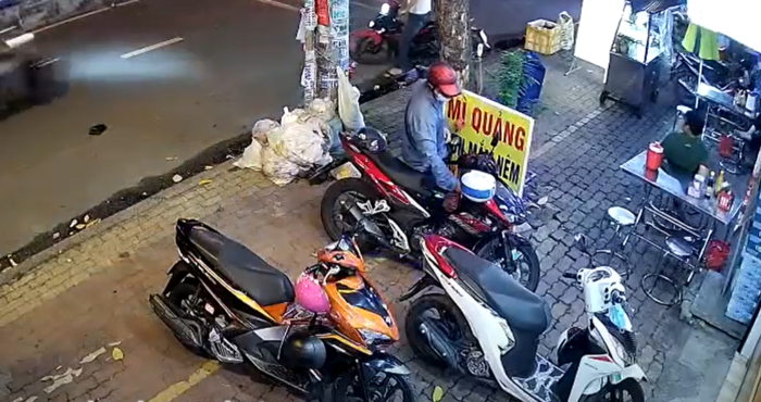 Nam thanh niên áo xanh, mũ bảo hiểm đỏ tiếp cận và bẻ khóa chiếc xe máy