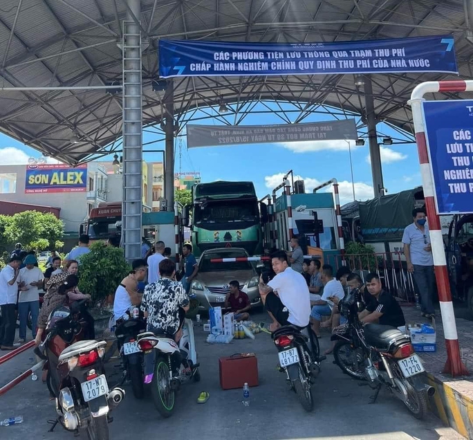 Một số người mang xe máy, loa kéo, đồ ăn uống... chặn trước barrier của trạm thu phí BOT trên Quốc lộ 39B - Ảnh: OFFB