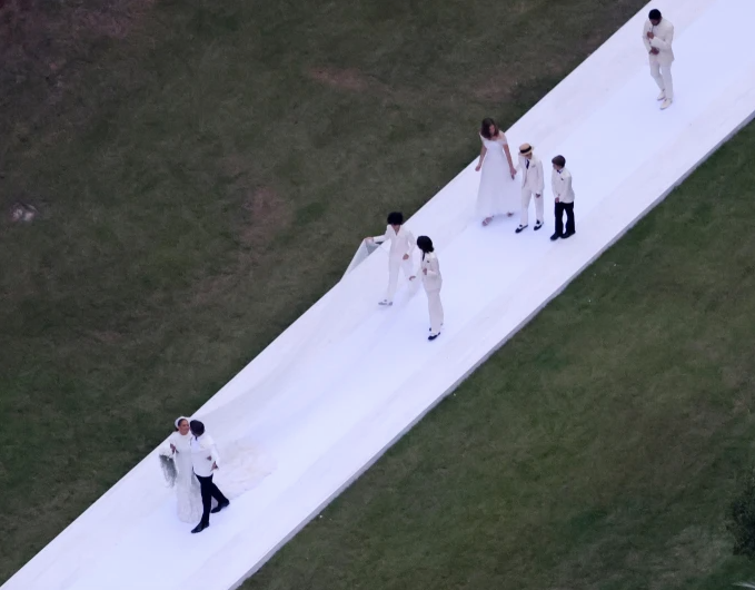  Các con của nữ diễn viên 'Marry Me' giúp nâng đuôi váy cho mẹ khi bước đi cùng chồng mới cưới vào lễ đường.