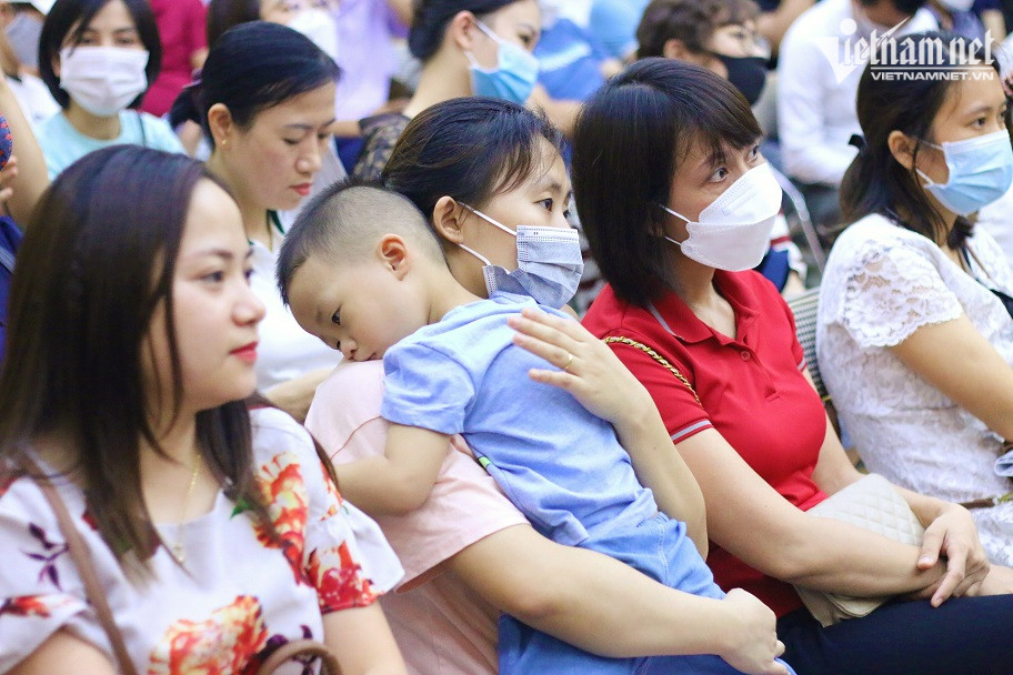 Phụ huynh bế theo con nhỏ đi bốc thăm giành suất học công lập của Trường Mầm non Hoàng Liệt, quận Hoàng Mai. Ảnh: Thanh Hùng