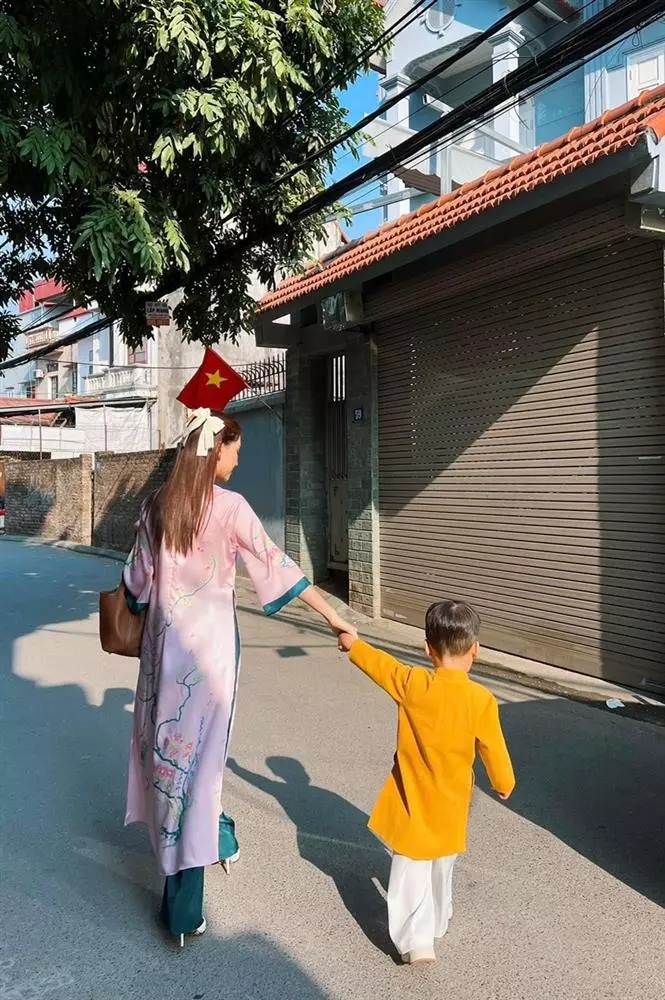 Bé Bo rạng rỡ trong bộ trang phục cổ truyền màu vàng cam rực rỡ, cùng mẹ đi du xuân