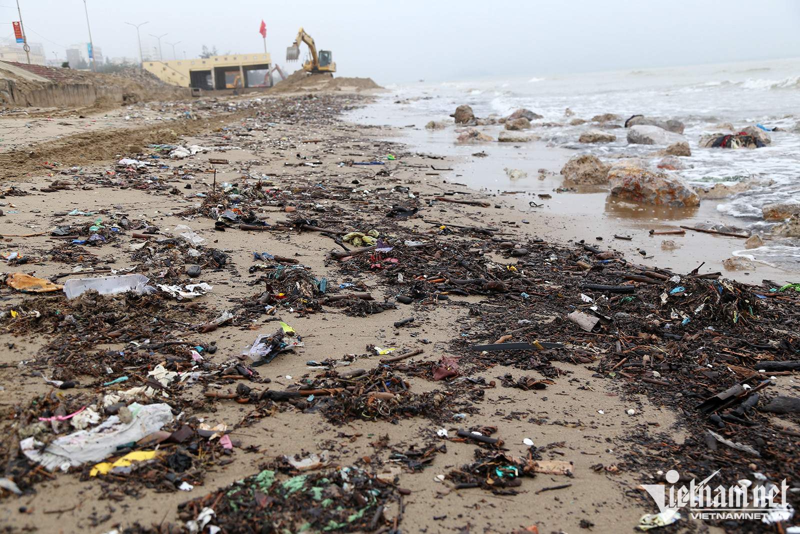 Máy móc đang thi công bờ kè biển Cửa Lò và lượng rác rất lớn dạt vào bờ biển - Ảnh: Quốc Huy